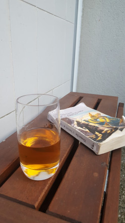 verre  avec un livre «L'instinct de léquarisseur» de Thomas Day sur une table en bois